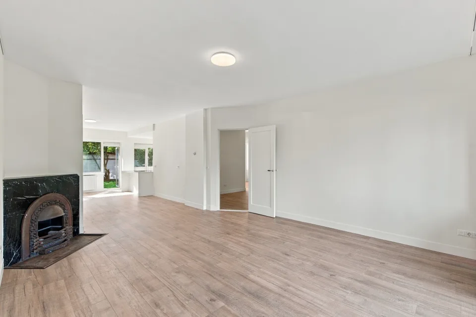 Woonkamer met marmeren schouw, houten vloer en doorkijk naar de eetkamer